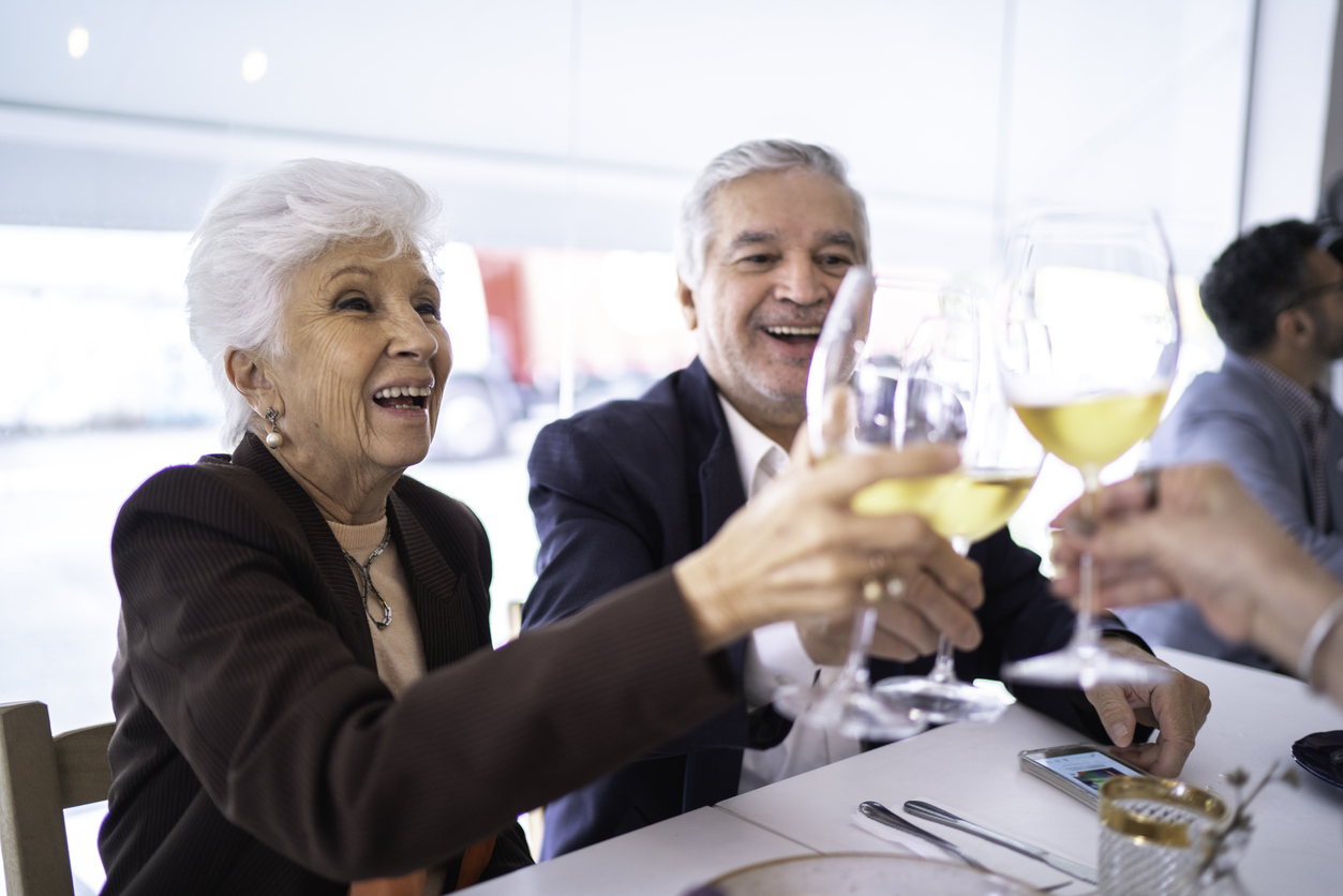 Senior friends toasting wine in restaurant
