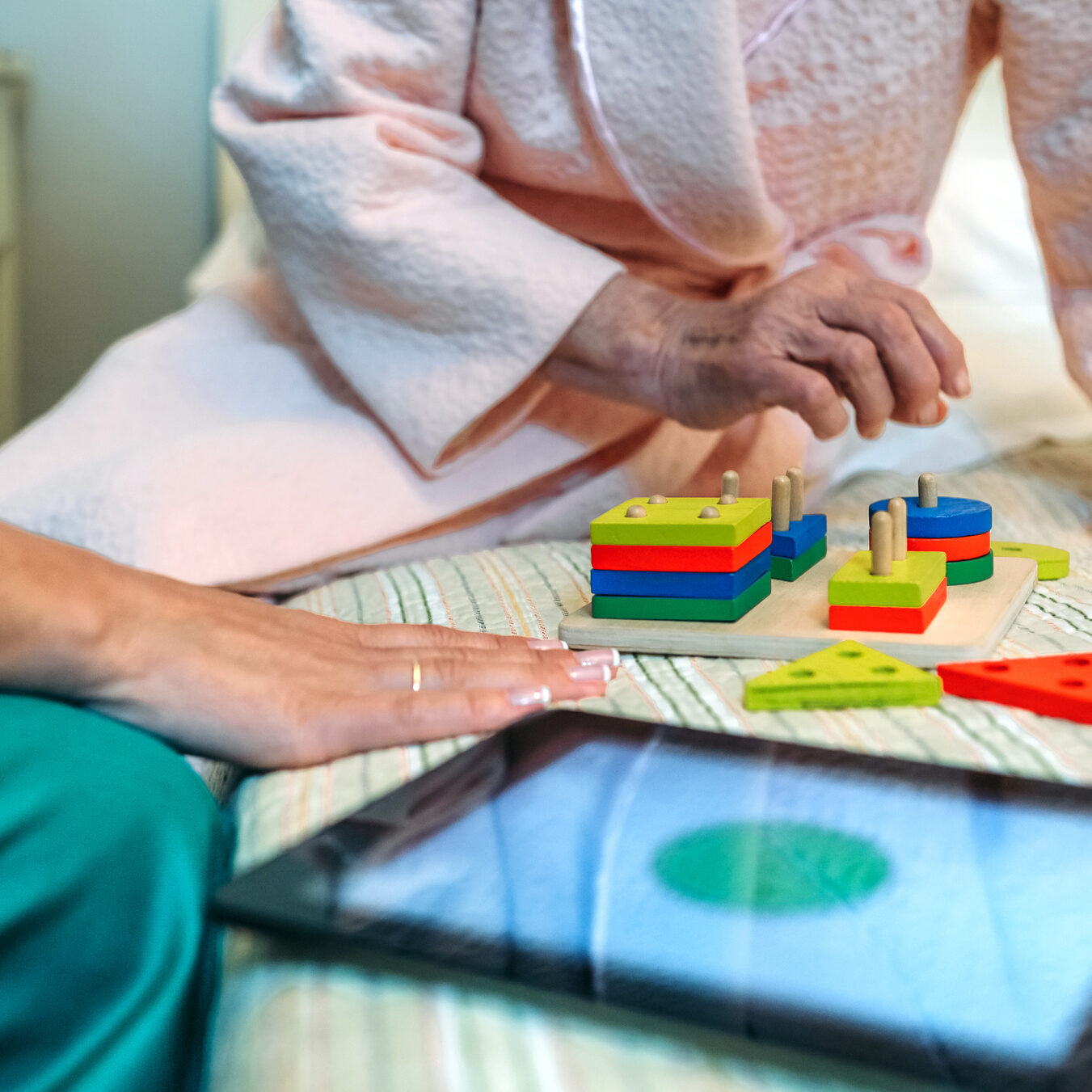Female doctor showing geometric shape game to elderly female patient with dementia